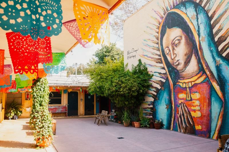 huge mural of girl praying placita mx courtyard