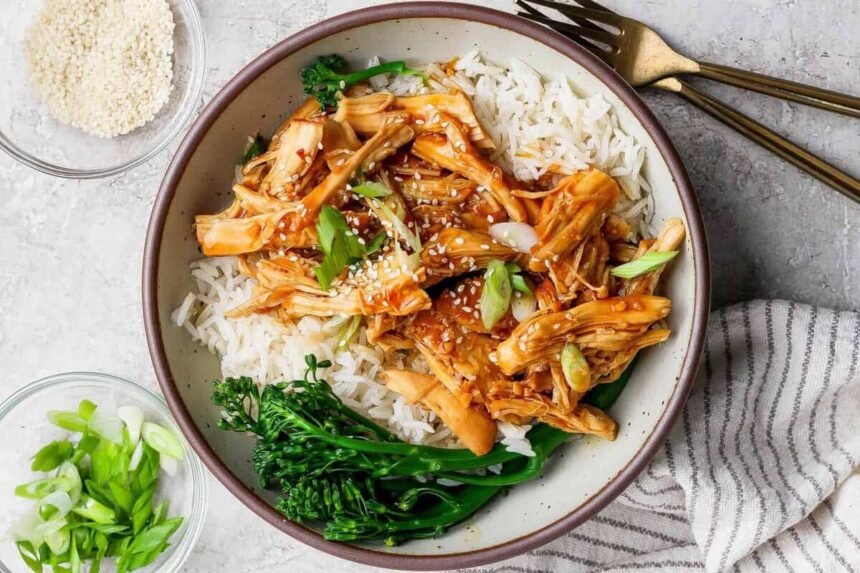 Crockpot honey garlic chicken served over white rice with broccolini in a bowl