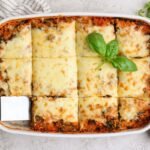 Overhead view of spinach quinoa lasagna casserole cut into squares in a baking dish
