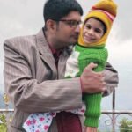 A father holds his young daughter outside.