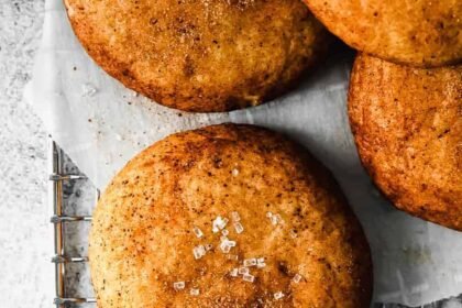 Four cinnamon buns on a cooling rack.