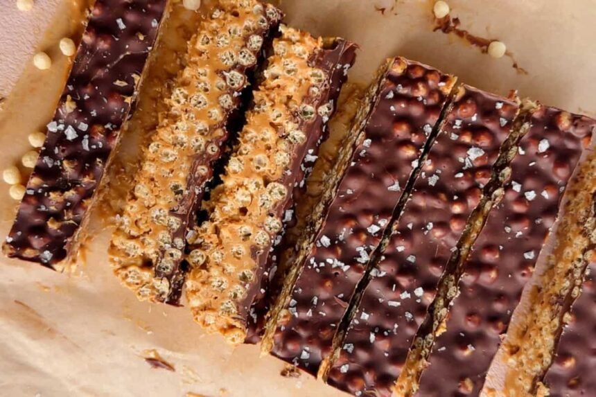 Rectangular chocolate and peanut butter crispy bars with a sprinkle of sea salt, arranged on parchment paper.