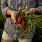 woman holding purple carrots with a chambray shirt on