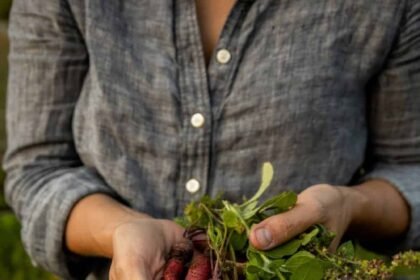 woman holding purple carrots with a chambray shirt on
