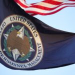 A flag with the seal of the Office of Personnel Management flies in the wind.