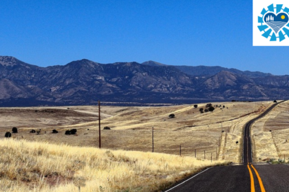 A landscape photo of an empty road heading over rolling hills towards a mountain range in rural Colorado. The Colorado Rural Health Transformation Program logo is visible in the upper right hand corner.