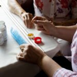 A close up shot of a woman sorting daily medication for a senior woman seated beside her.