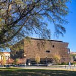 brown building of the national museum of african american history framed by tree