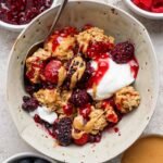 protein berry crumble served in a bowl with yogurt and peanut butter drizzle