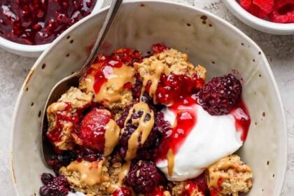 protein berry crumble served in a bowl with yogurt and peanut butter drizzle