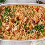 Salmon casserole with rice noodles, baked salmon chunks, cashews, green onions, cilantro, and chili crunch Boursin sauce in a white baking dish